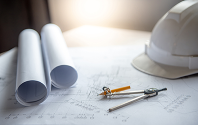 construction blueprints, documents rolled up, protractor with pencil and safety helmet on a table